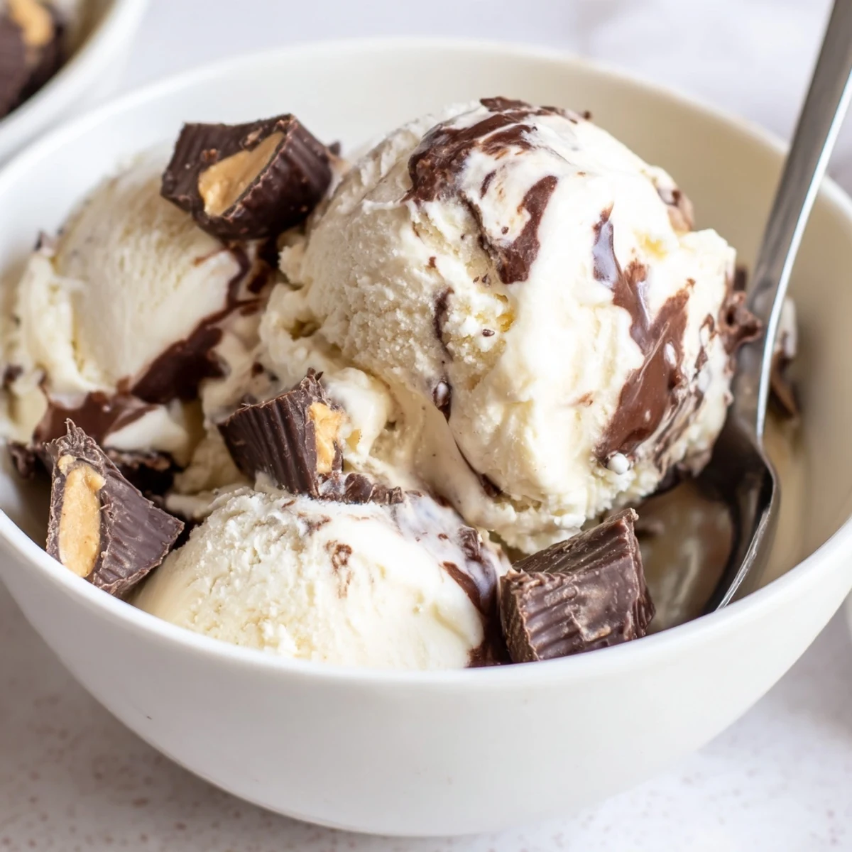 Scoop of rich vanilla Moose Tracks ice cream topped with chocolate peanut butter cups