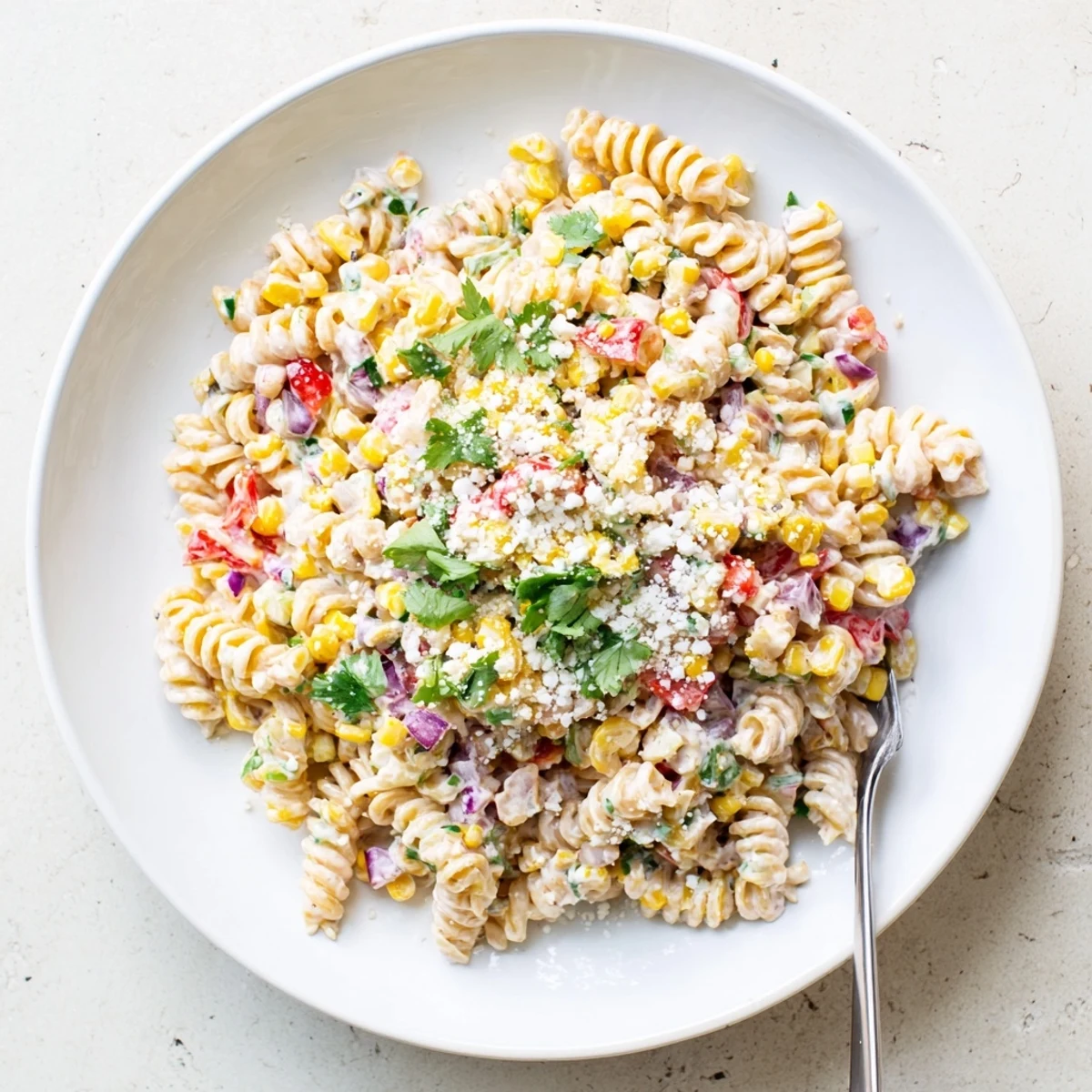 Creamy Mexican Street Corn Pasta Salad tossed with zesty lime, sweet grilled corn, and crumbled white cheese for a refreshing summer side