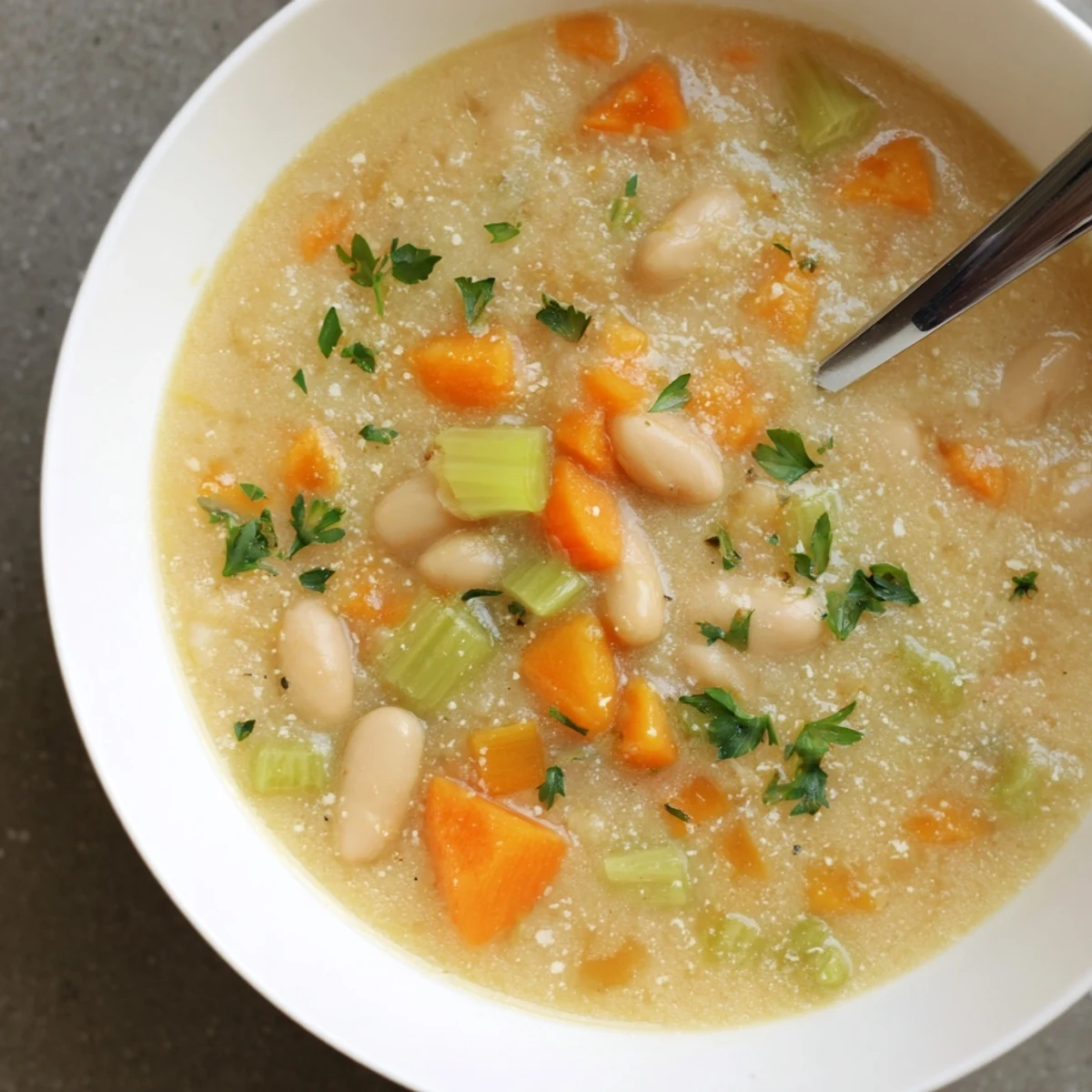 Savory garlic rosemary white bean soup in rustic bowl with drizzled olive oil