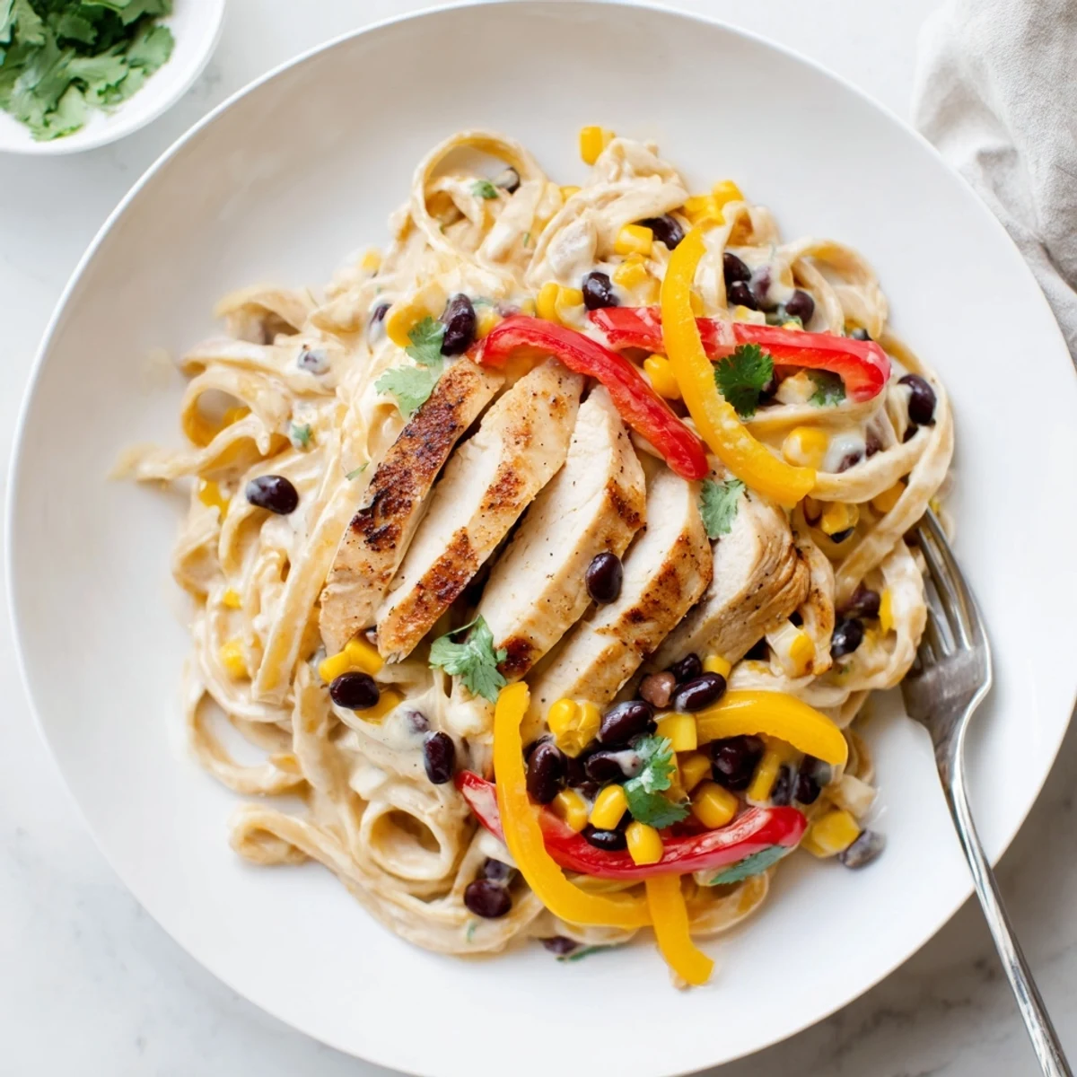Creamy Southwest chicken alfredo pasta with colorful peppers and black beans in a rich white sauce
