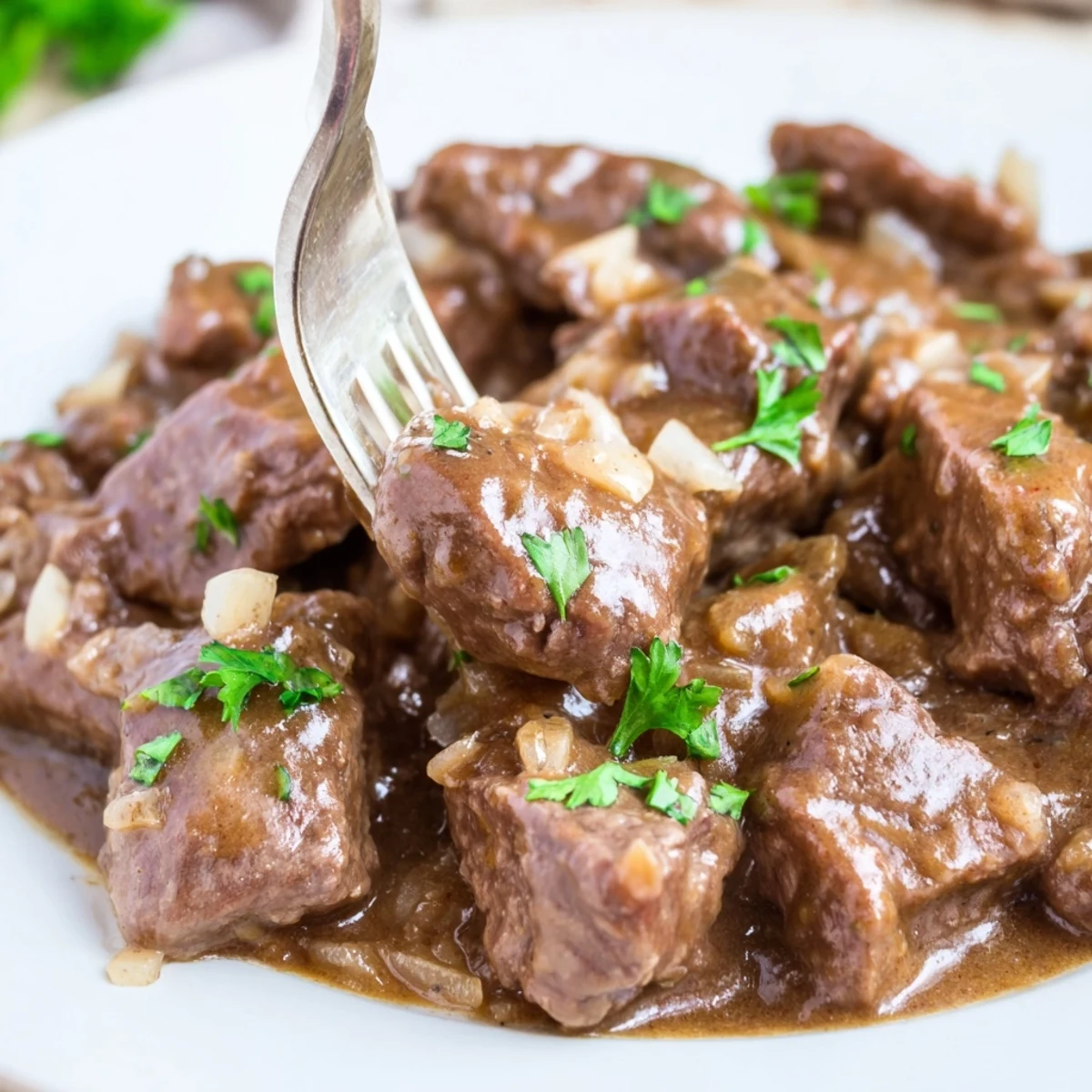 Fork-tender slow cooker beef tips and gravy bowl with thick savory sauce and diced onions
