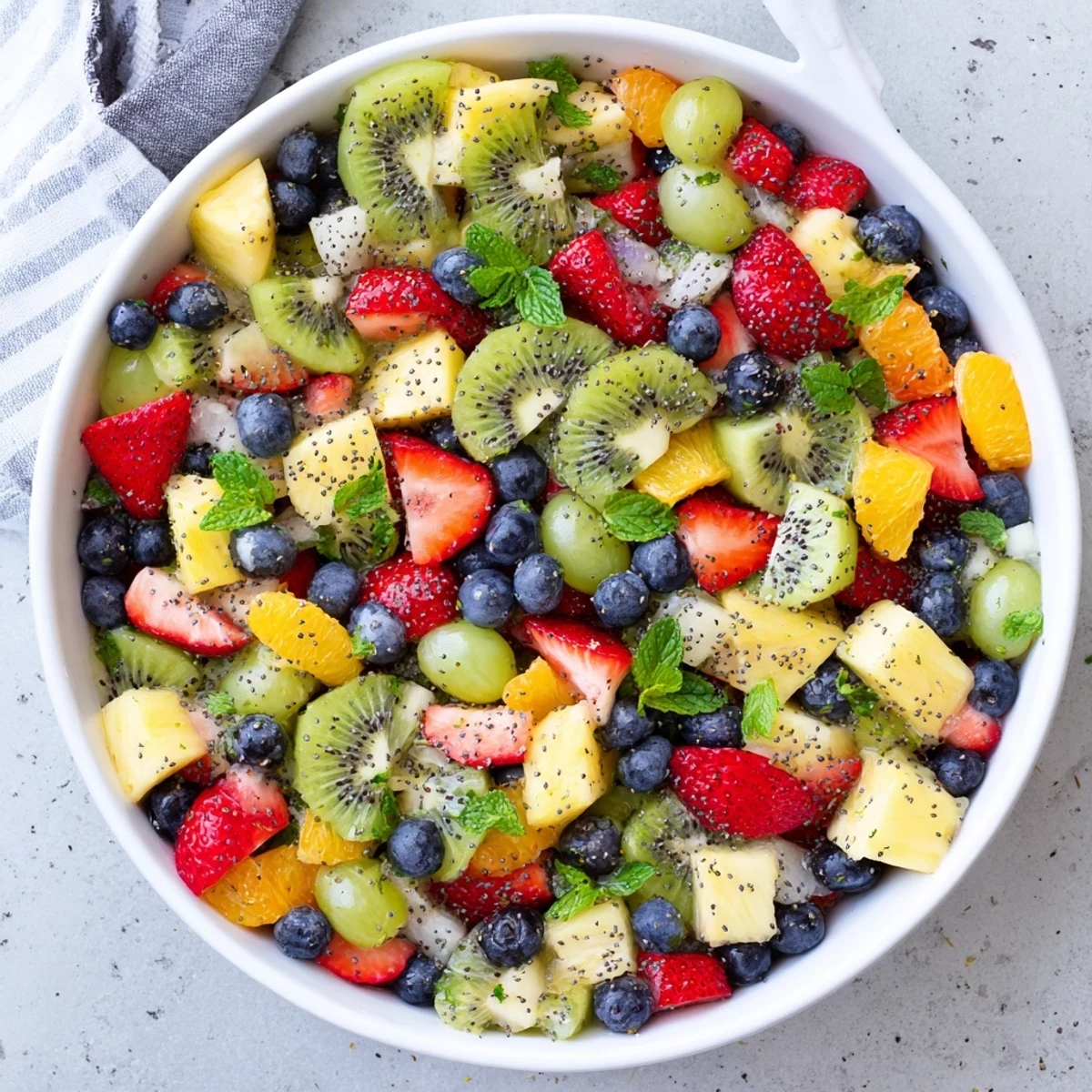 Glass serving dish displaying festive Easter fruit salad with juicy berries, citrus slices, and poppy seed glaze