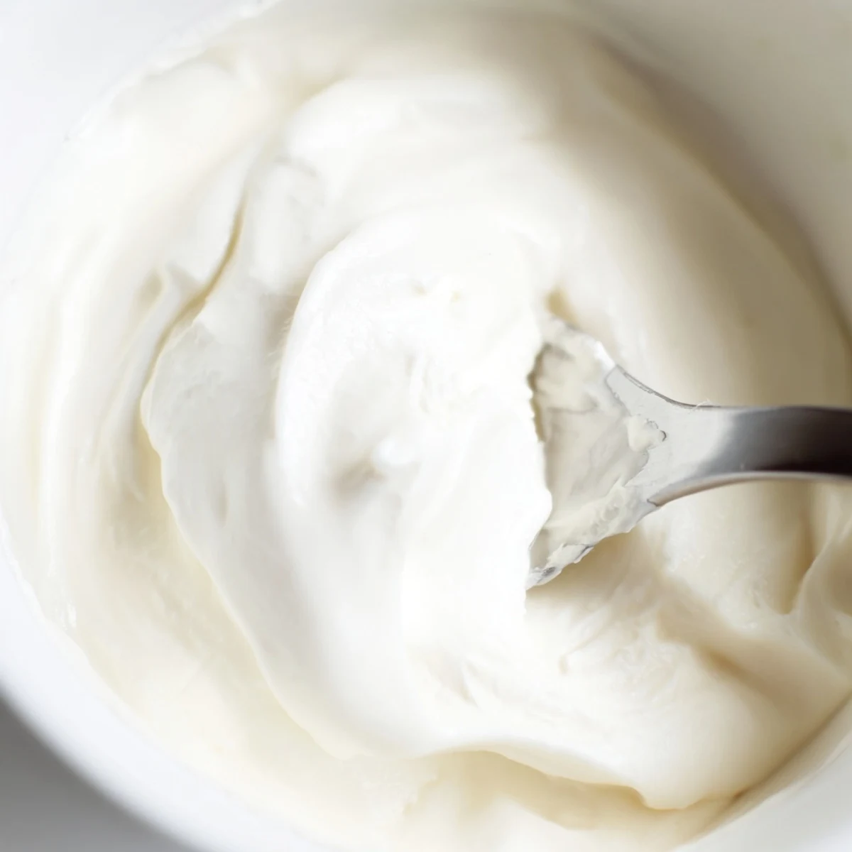 Homemade Greek yogurt in a white bowl topped with fresh honey drizzle and blueberries