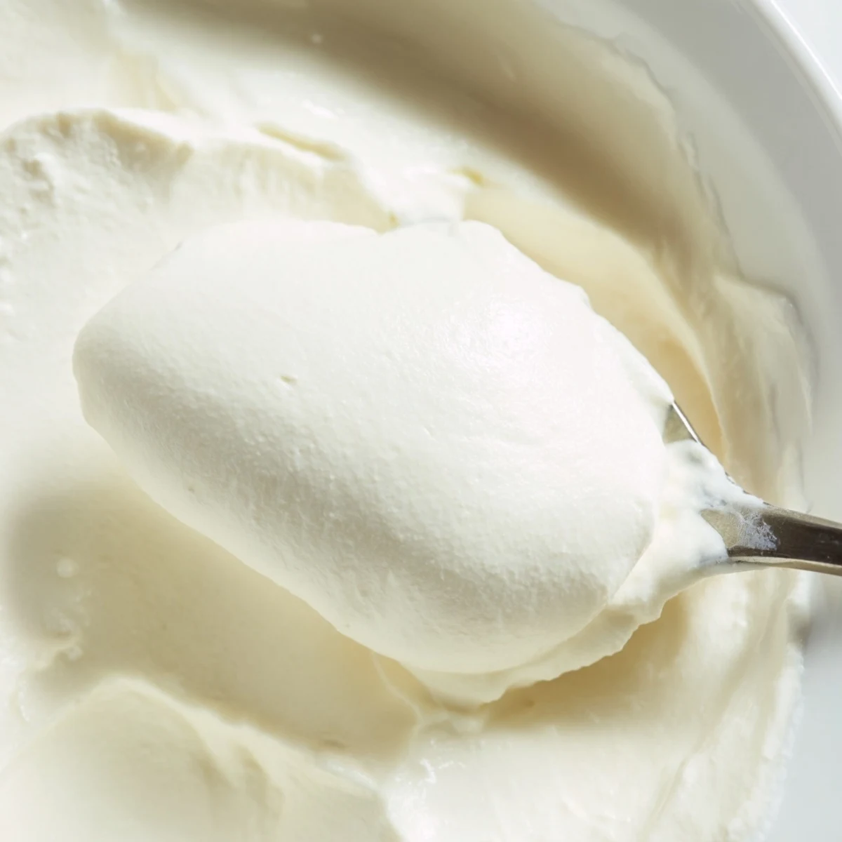 Thick creamy Greek yogurt strained through cheesecloth in a glass bowl over kitchen counter