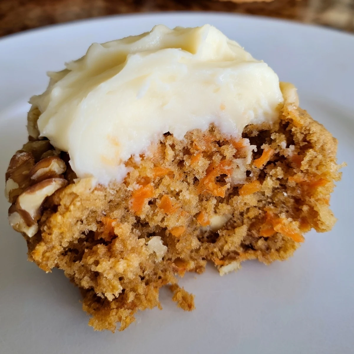 Soft Crumbl carrot cake cookies with swirled cream cheese frosting on rustic white plate