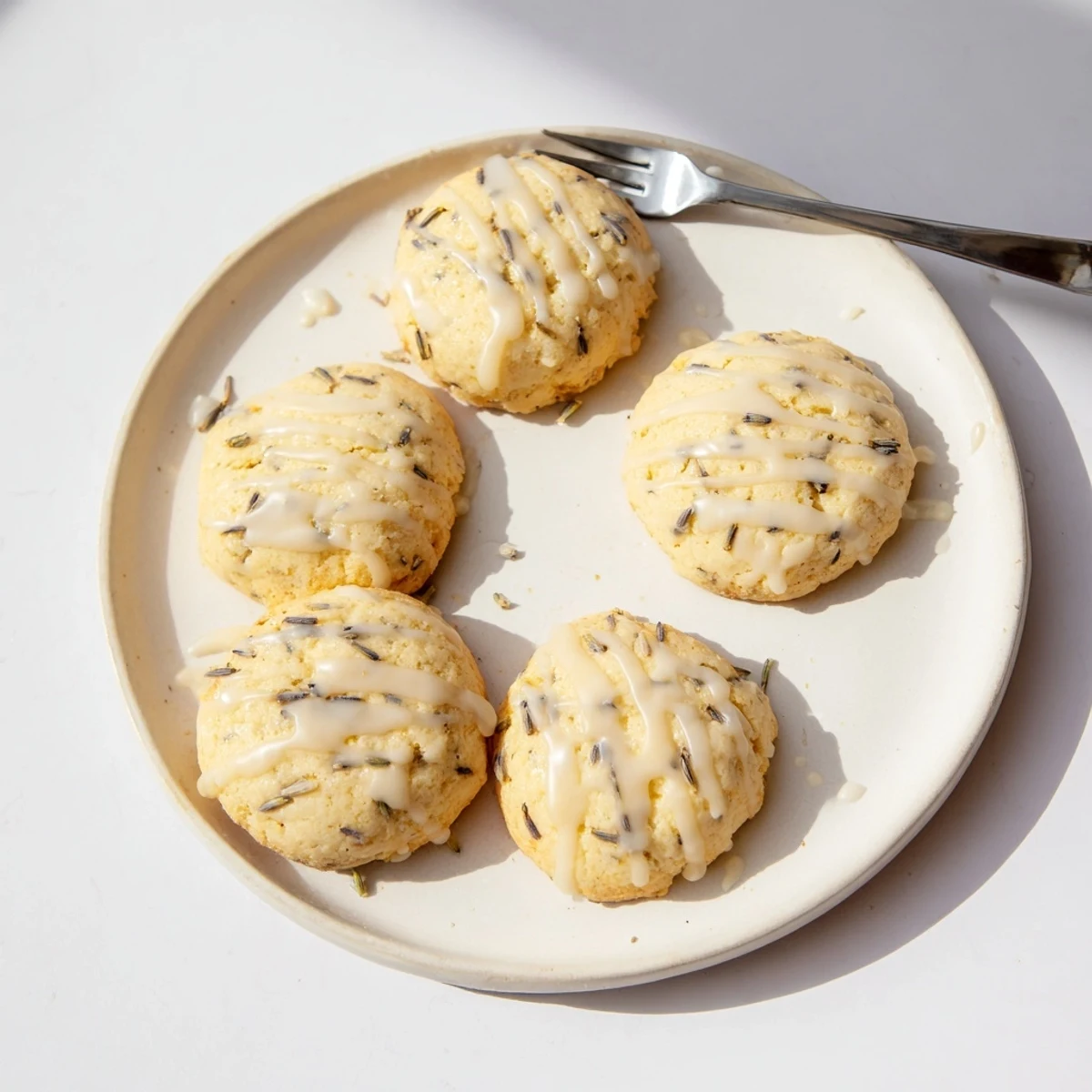 Golden lemon lavender cookies with speckled lavender buds on a rustic white plate