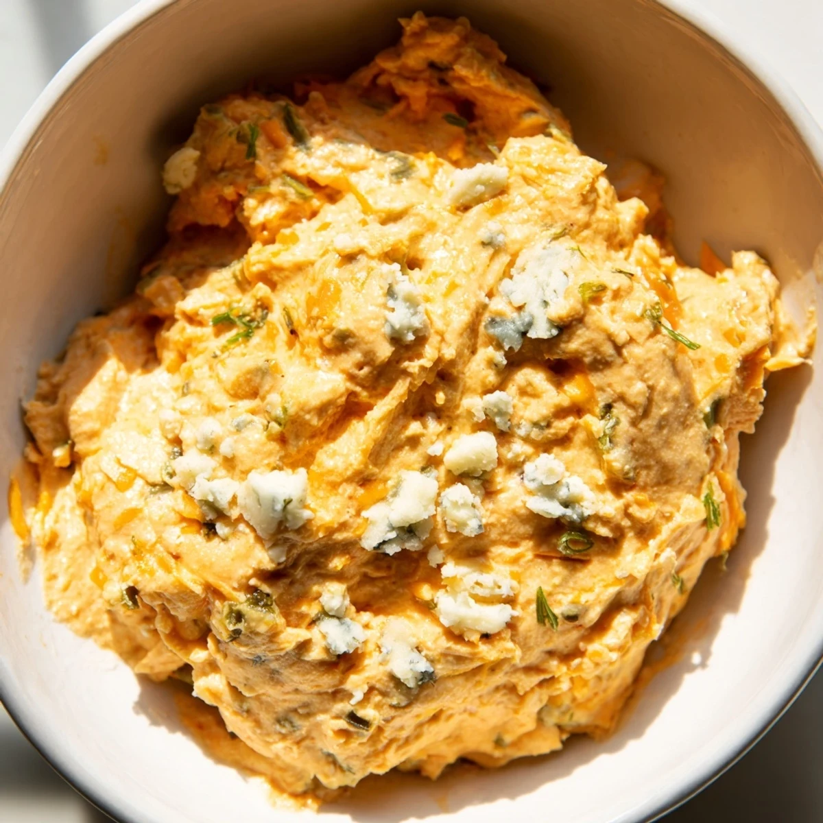 Tangy buffalo pickle dip topped with fresh chives and sliced pickles on a rustic board
