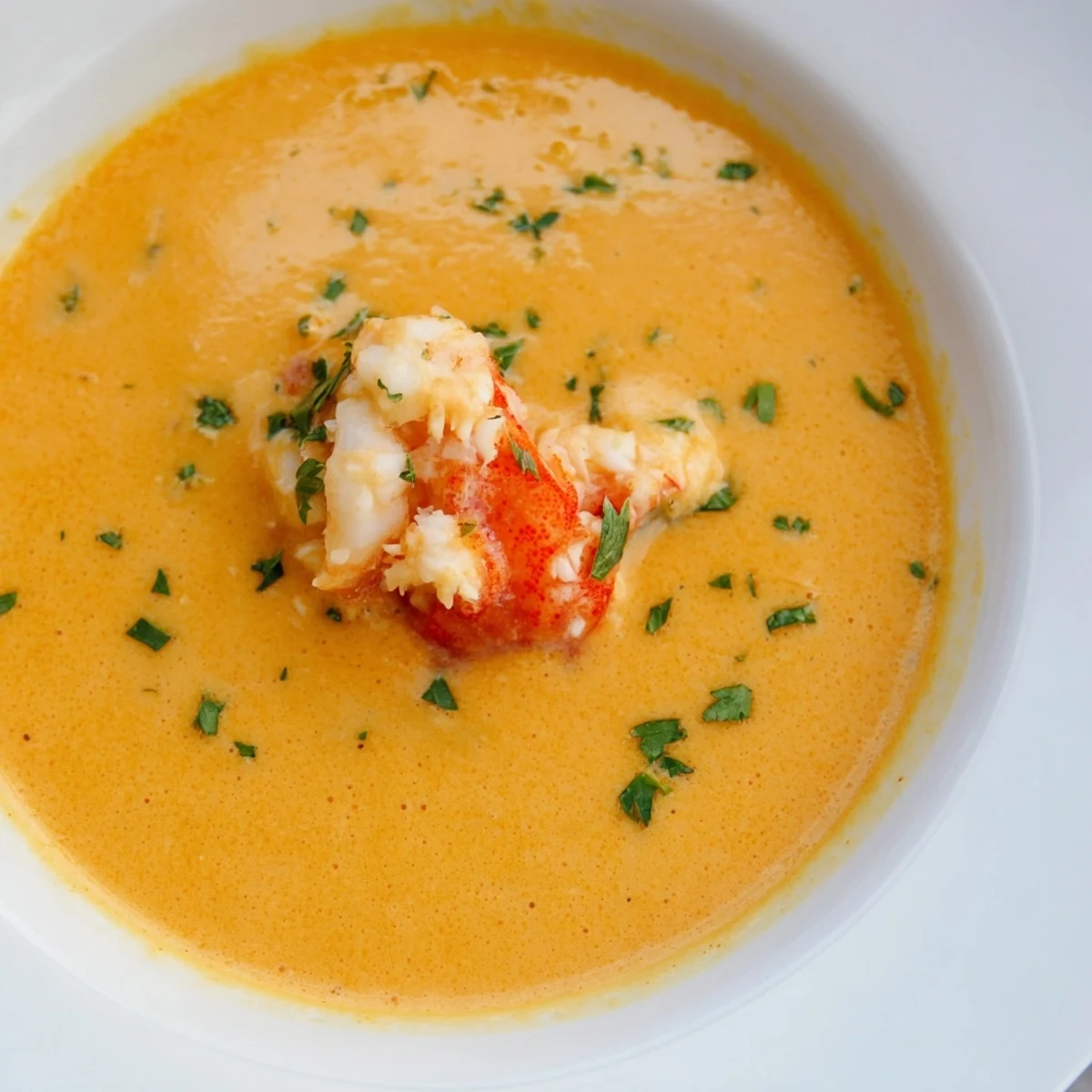 Velvety creamy crab and shrimp bisque garnished with fresh parsley in a warm bowl