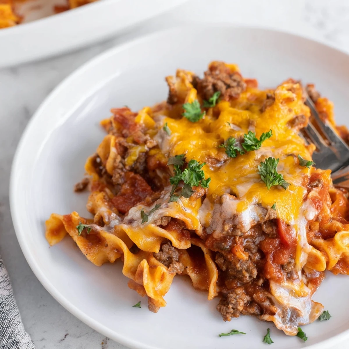 Beef Noodle Casserole bubbling with melted cheddar, tender noodles, fragrant tomato sauce