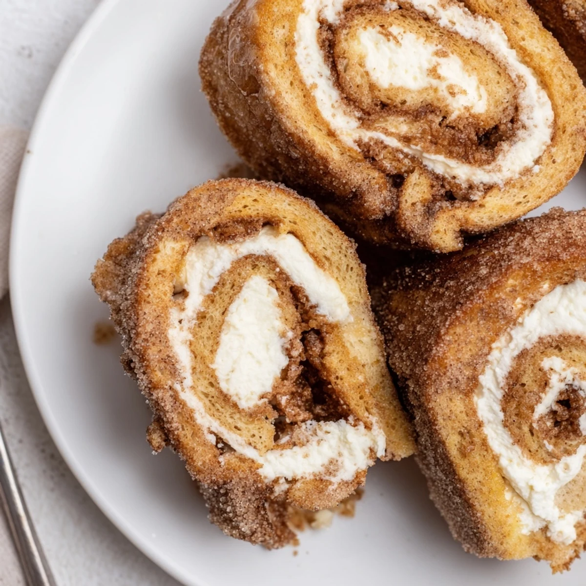 Skillet-browned Cinnamon Roll French Toast Roll Ups with sticky cinnamon-sugar and maple drizzle.