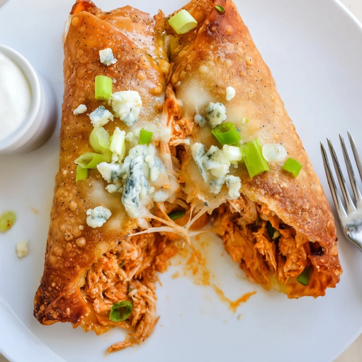 Buffalo Chicken Egg Rolls with golden crispy shell, melty cheese oozing, served with ranch