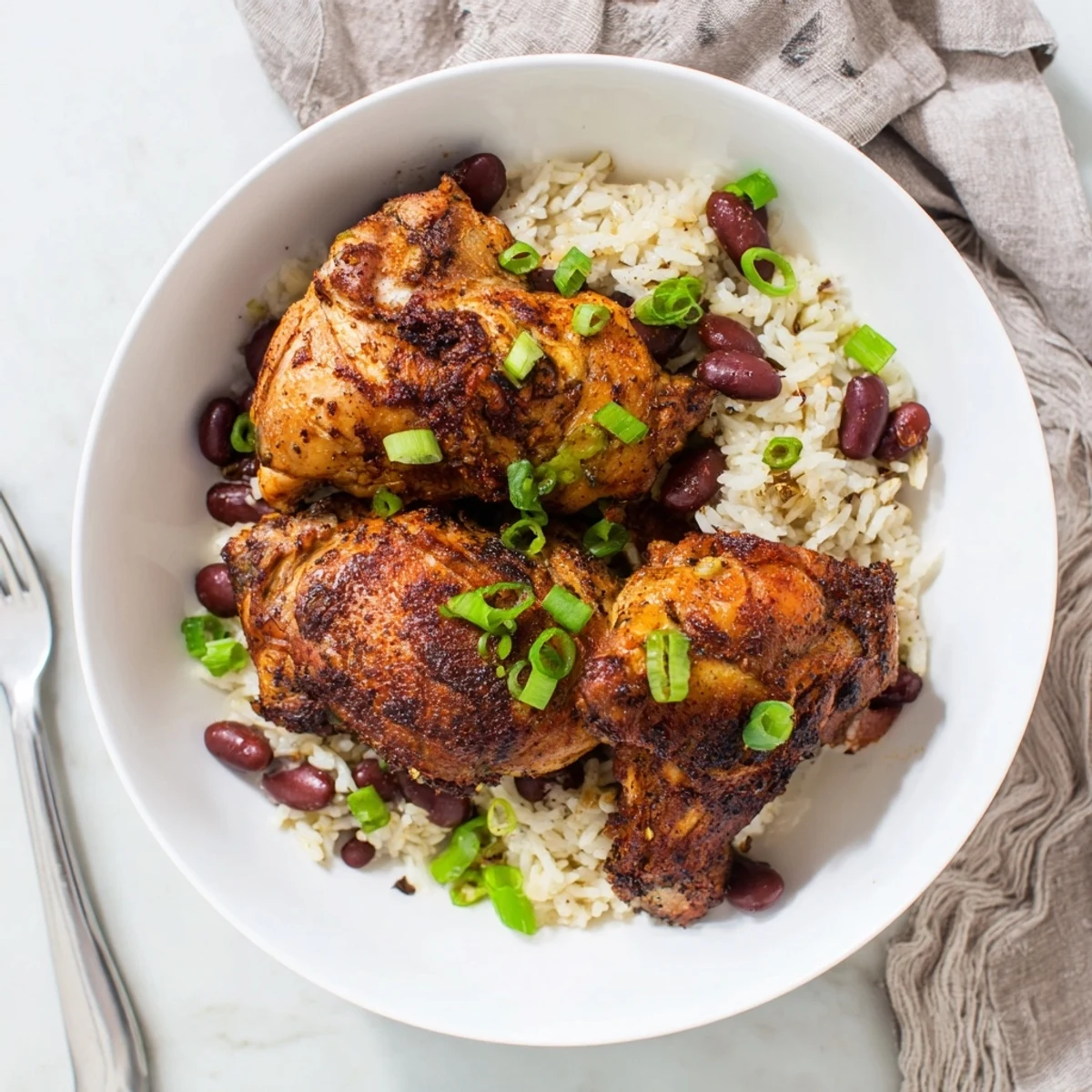 Golden brown Caribbean jerk chicken thighs resting over fluffy coconut rice with red kidney beans