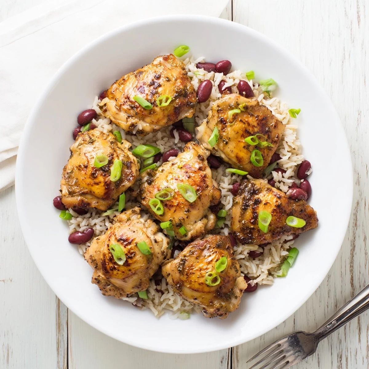 Spicy jerk seasoned chicken plated on fragrant coconut rice and beans garnished with fresh green onions