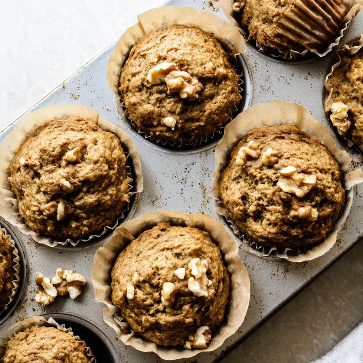 Golden butternut squash banana muffins topped with walnuts on a wooden board
