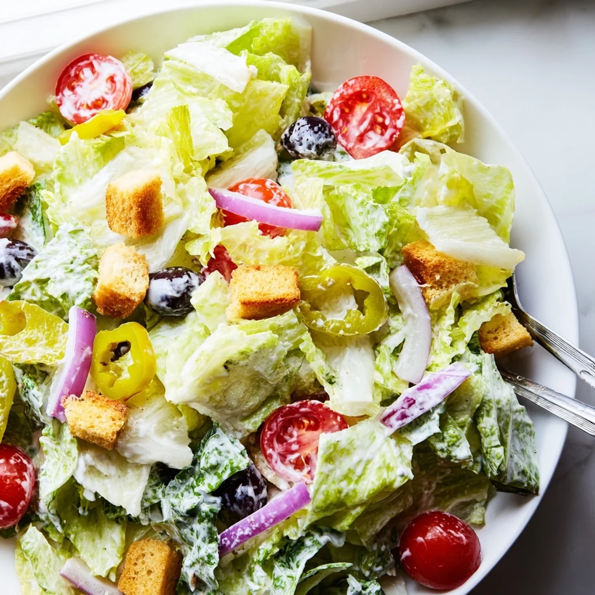 Crisp Olive Garden Salad topped with juicy tomatoes, olives, and creamy dressing