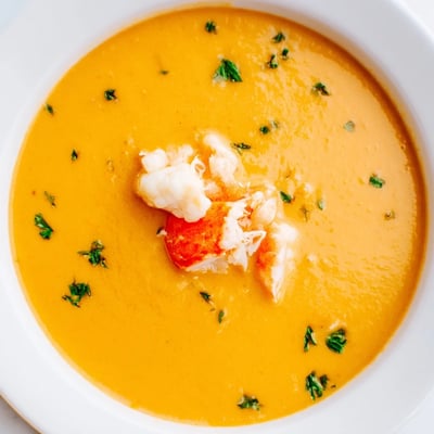 Golden creamy crab and shrimp bisque ladled into rustic bowls with crusty bread alongside